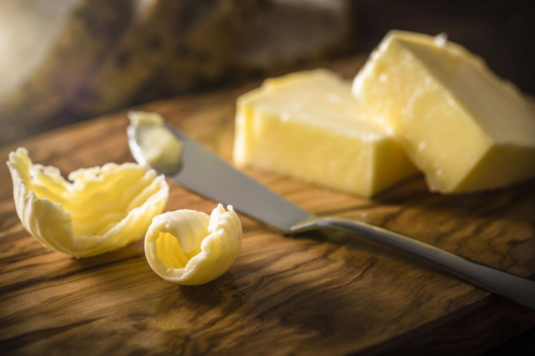 Butter curl and butter knife on a wooden cutting board